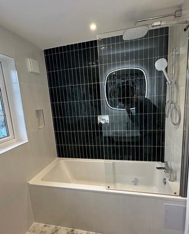 A mid-tier bath-and-shower install with feature tiling and backlit mirror — typical specification at the £9K–£12K bracket.
